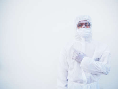 Asian male doctor or scientist in PPE suite uniform showing pointing fingers away at copy space while standing and looking forward. coronavirus or COVID-19 concept isolated white backgroundの写真素材