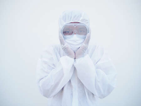 Asian doctor or scientist in PPE suite uniform covers ears with hands. Danger of coronavirus or...