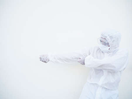 Asian doctor or scientist in PPE suite uniform showing tries to pull a strong invisible rope on a white background. coronavirus or COVID-19 conceptの写真素材