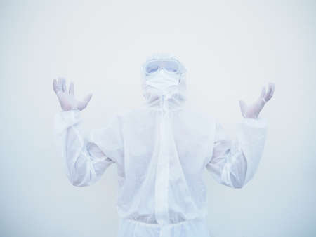 Positive young doctor or scientist in PPE suite uniform raising both hands to empty space above. coronavirus or COVID-19 concept isolated white backgroundの写真素材