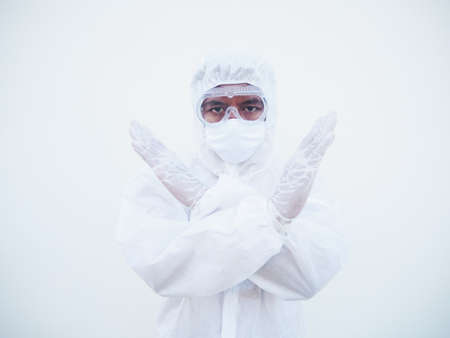 Asian doctor or scientist in PPE suite uniform showing x sign with his arms to stop doing something while looking ahead.  gesturing stop, warning of danger. coronavirus or COVID-19 concept isolated white backgroundの写真素材
