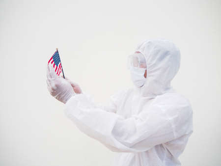 Portrait of doctor or scientist in PPE suite uniform holding national flag of United states of America. COVID-19 concept isolated white backgroundの写真素材