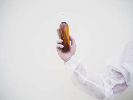 Portrait of doctor or scientist in PPE suite uniform holding plastic bottle with skin care product....