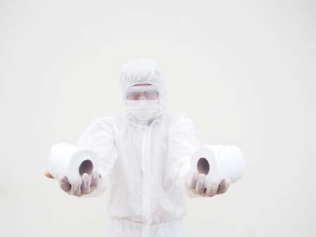 Asian male doctor or scientist in PPE suite uniform holding toilet paper. Lack of toilet paper in the quarantine of coronavirus. COVID-19 concept isolated white backgroundの写真素材