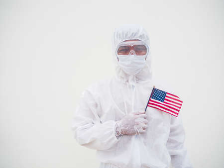 Portrait of doctor or scientist in PPE suite uniform holding national flag of United states of...