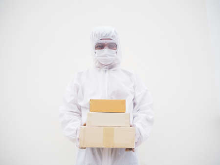 Young man in PPE suite uniform while holding cardboard boxes in medical rubber gloves and mask....