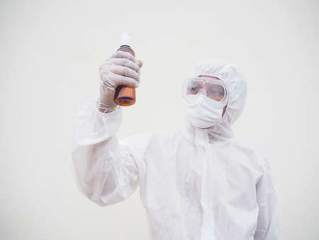 Portrait of doctor or scientist in PPE suite uniform holding plastic bottle with skin care product. COVID-19 concept isolated white backgroundの写真素材