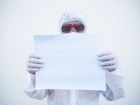 Young doctor or scientist in PPE suite uniform holding blank paper for text with both hands While...