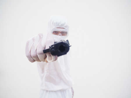 Portrait of doctor or scientist in PPE suite uniform holding gun. COVID-19 concept isolated white...