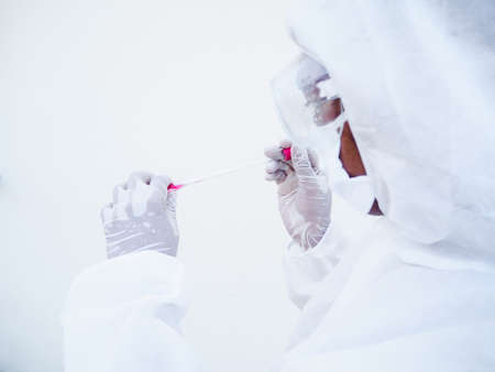 Asian doctor or scientist in PPE suite uniform. Personal protective equipment suit dropping a blood...