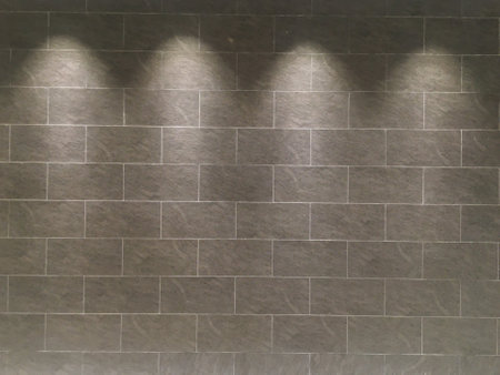 Interior room featuring a brick wall, vintage wooden floor, and four spotlight fixtures, creating a retro ambiance.の写真素材