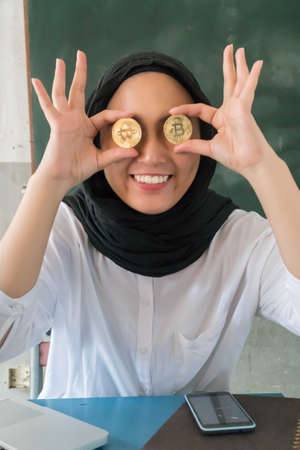 Happy young woman wearing hijab Holding Bitcoin Moneyの写真素材