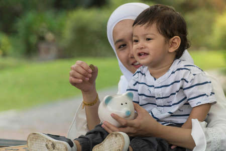 Mother and son holding coins and piggy bank, saving conceptの写真素材