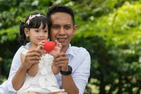 Father and daughter holding heart shape soft toy, healthy family conceptの写真素材