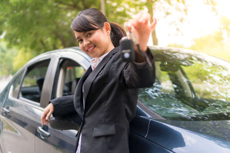 Cute Asian girl holding car keys and smiling e-hailing conceptの写真素材