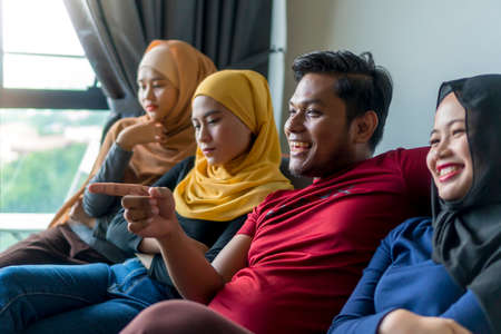 Polygamy concept husband with 3 wife at the sofa watching televisionの写真素材