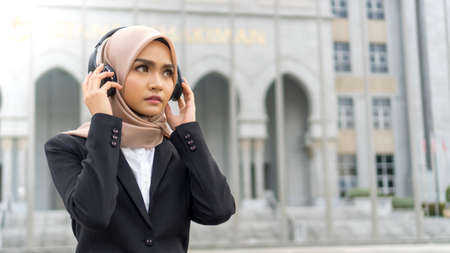 Cute Malay Woman wearing headset outdoor listening to the music having funの写真素材