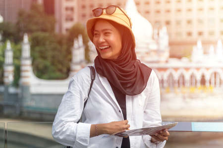 Travel Concept, Muslim Tourist Couple at Kuala Lumpur holding a map and smile