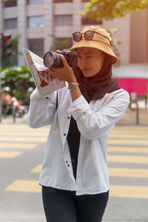 Travel Concept, Portrait of Cute Malay Asian Lady wearing hijab outdoor holding cameraの写真素材