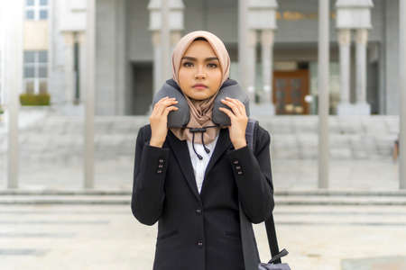 Business Travel concept, cute malay woman using travel pillow outdoor