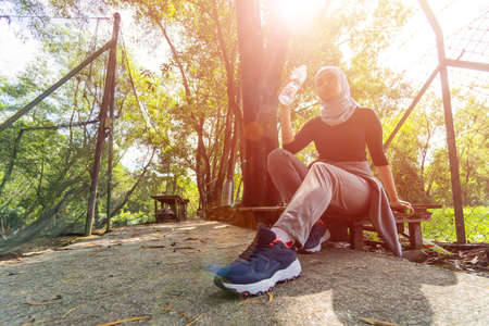 Healthy Lifestyle Concept, Malay Muslim lady wearing hijab outdoor resting and drink waterの写真素材