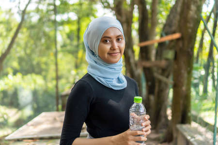 Healthy Lifestyle Concept, Malay Muslim lady wearing hijab outdoor resting and drink water