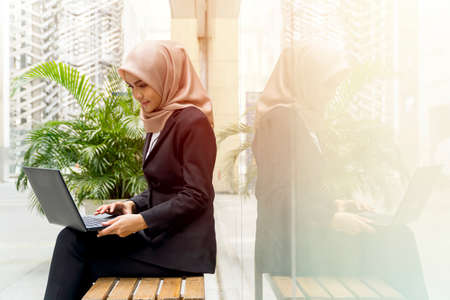 Business Lifestyle, Cute Malay Woman wearing hijab outdoor using laptop sitting on the bench