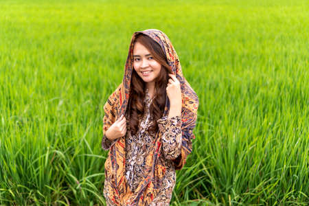 Asian Malay lady wearing traditional cloth outdoor over the green paddy backgroundの写真素材