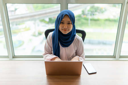 Working from home concept, Malay lady using laptop at home