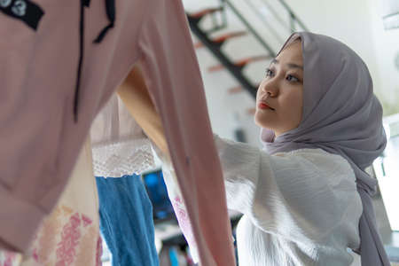 Lifestyle at home, cute malay woman doing routine housework by folding her laundryの写真素材