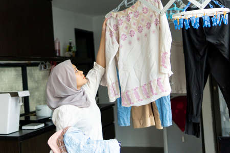 Lifestyle at home, cute malay woman doing routine housework by folding her laundry