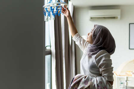 Lifestyle at home, cute malay woman doing routine housework by folding her laundryの写真素材