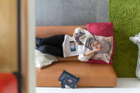 Lifestyle at home, cute malay woman at the sofa reading booksの写真素材
