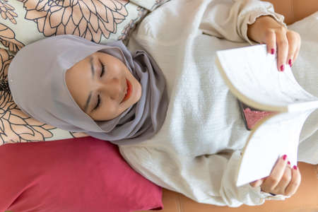 Lifestyle at home, cute malay woman at the sofa reading booksの写真素材