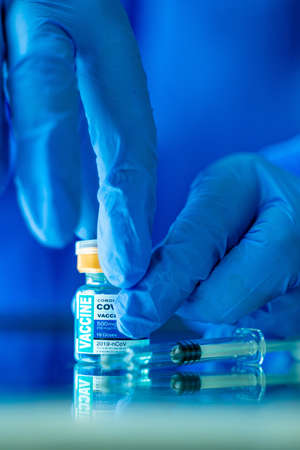 Women wearing PPE suit holding virus  Vaccine Vials and syringe soft focusing