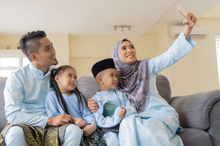 Eid Mubarak celebration moment, Malay family wearing traditional cloth looking at the cameraの写真素材