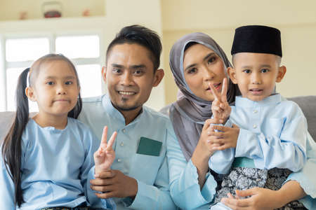 Eid Mubarak celebration moment, Malay family wearing traditional cloth looking at the camera