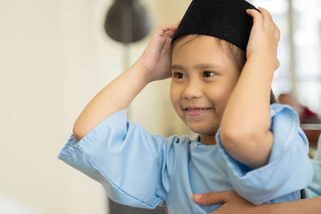 Eid Mubarak celebration moment, smiling child playing songkokの写真素材