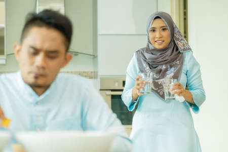 Eid Mubarak celebration moment, young wife preparing food for husband. Happy asian family