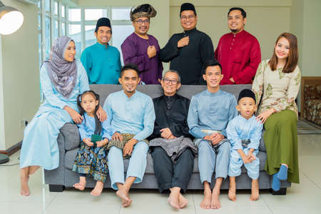 Eid Mubarak celebration moment, big family photo at the sofa wearing traditional cloth. Happy asian familyの写真素材
