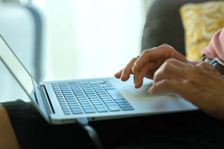 Technology concept, Close-up hands of senior citizen using laptop at home. Work from homeの写真素材