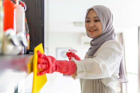 Lifestyle at home, cute malay woman doing housework by cleaning the kitchenの写真素材