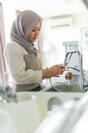 Lifestyle at home, cute malay woman doing housework by washing dishesの写真素材