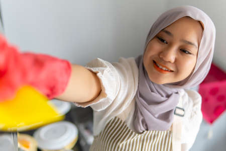 Lifestyle at home, cute malay woman doing housework by cleaning the kitchenの写真素材