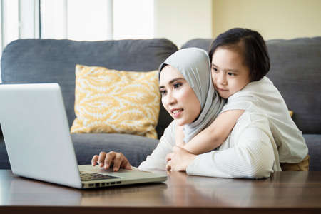 Family lifestyle concept, mother and daughter moment at the living room looking at the laptop