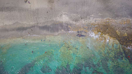 LAMALERA, NUSA TENGGARA, INDONESIA - DEC 13, 2018: Locals playing with the captured pilot whale near the shore while others are fishing at Lamalera Indonesiaのeditorial素材