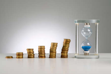 Finance Concept: Copy Space and arrangement of gold coin stack and hourglass sand timer