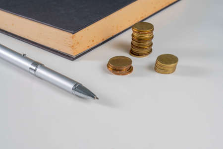 Finance Concept: Copy Space and arrangement of gold coin stack, pen and old bookの写真素材