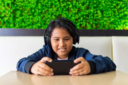 E-Sport concept: Young boy wearing headset playing games using smartphone