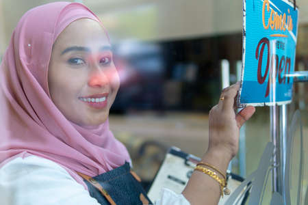 Business Concept : Young restaurant waiter holding open signboard and smile business re-openの写真素材